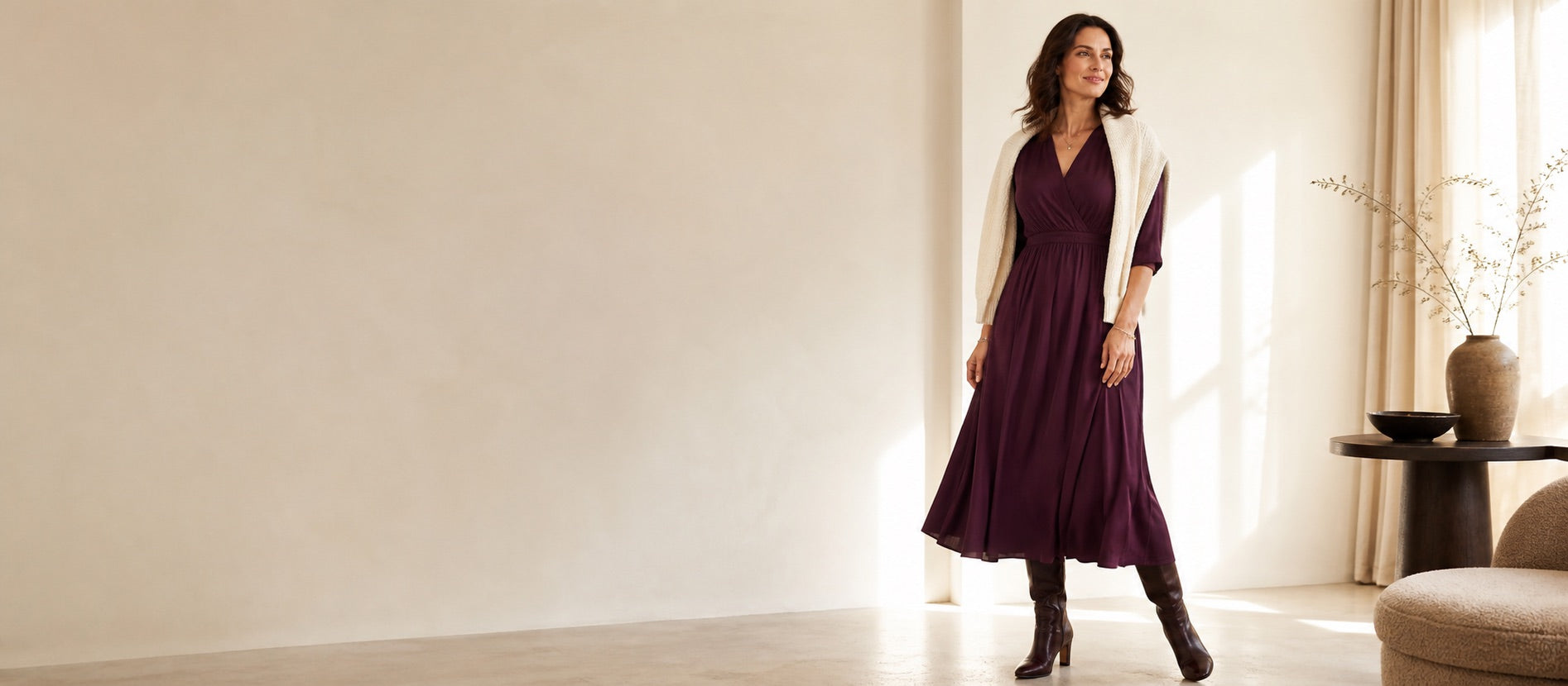 A woman in a deep plum midi dress in a sunlit atelier